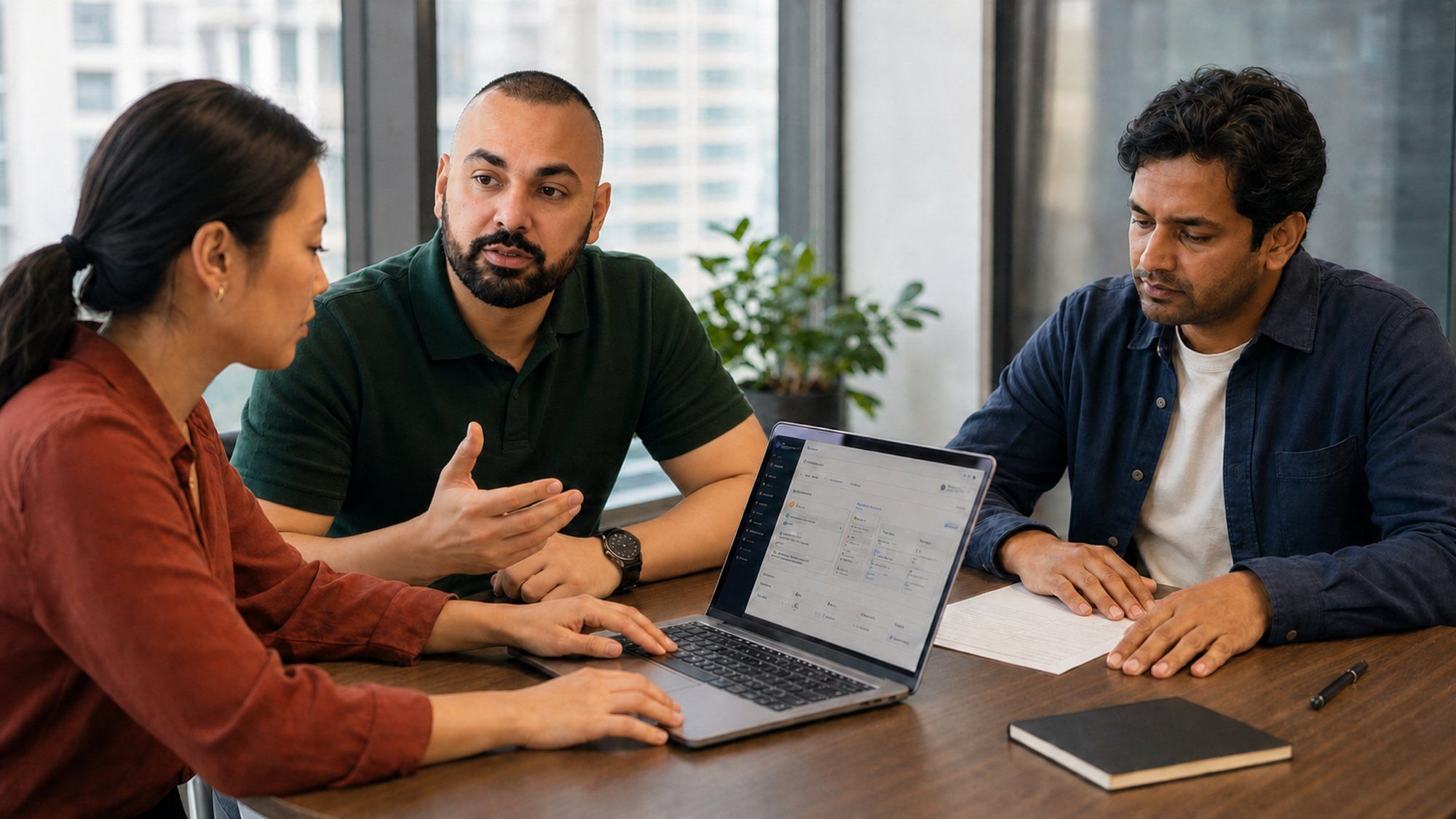 Rahim Syed walking two colleagues through a property platform dashboard on a laptop in a client meeting